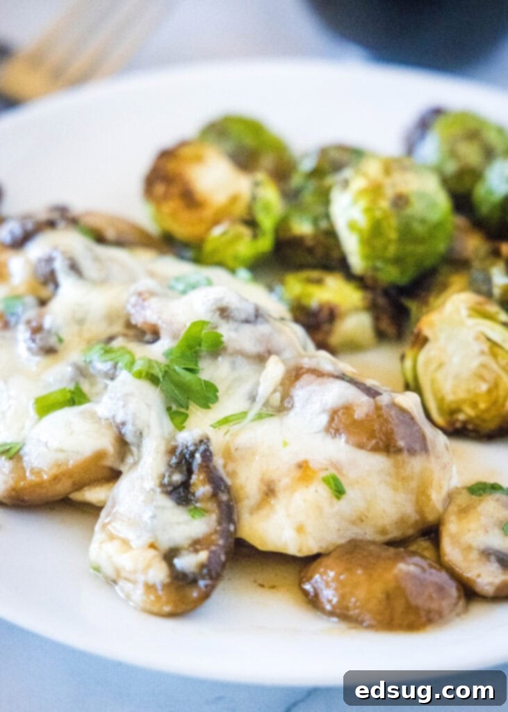 Chicken Lombardy 2 chicken with mushrooms and cheese on a white plate with brussel sprouts