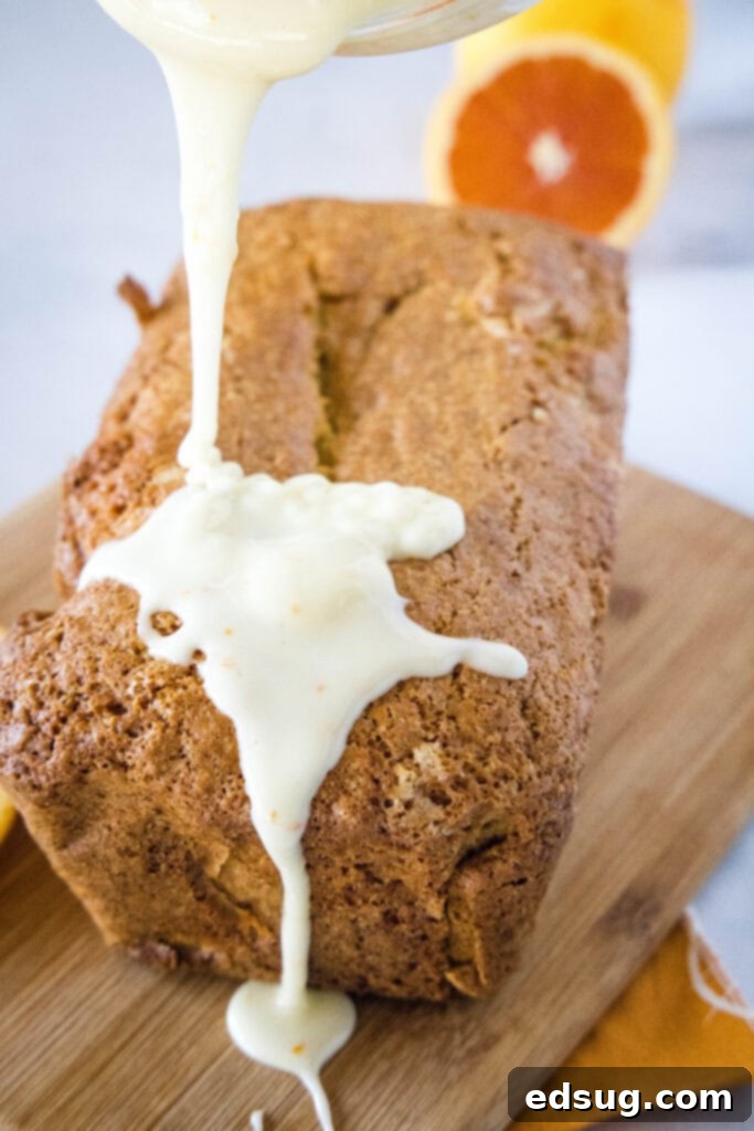 Zesty Orange Loaf 4 pouring orange glaze over freshly baked orange bread on a cutting board