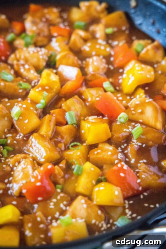 Aloha Pineapple Chicken 2 A large skillet brimming with colorful Hawaiian Chicken stir-fry, featuring chicken, bell peppers, and pineapple in a glossy sauce.