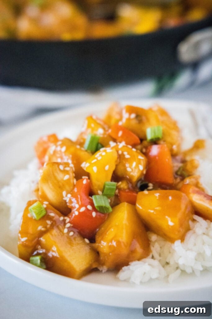 Aloha Pineapple Chicken 4 A plate of Hawaiian Chicken stir-fry served over a bed of white rice, garnished with fresh herbs.