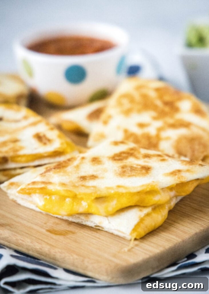 Melty Cheese Quesadilla 2 Crispy cheese quesadilla halves on a rustic cutting board, ready to be enjoyed.