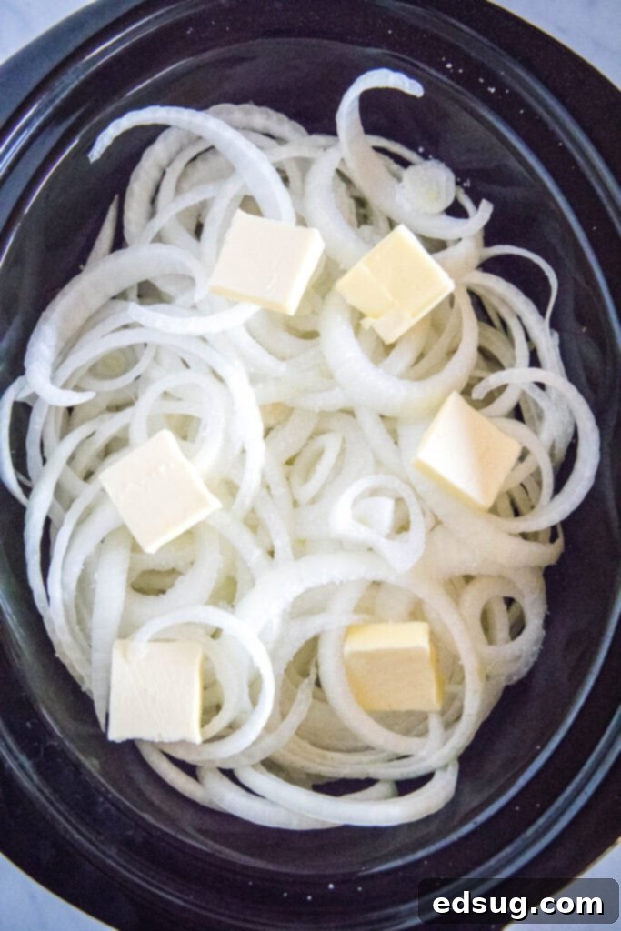 Slow Cooked Onion Perfection 4 Sliced raw sweet onions and pats of butter arranged in a crockpot before cooking.
