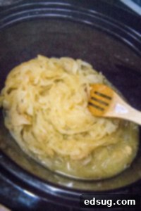cooked onions in a crockpot with a wooden spoon