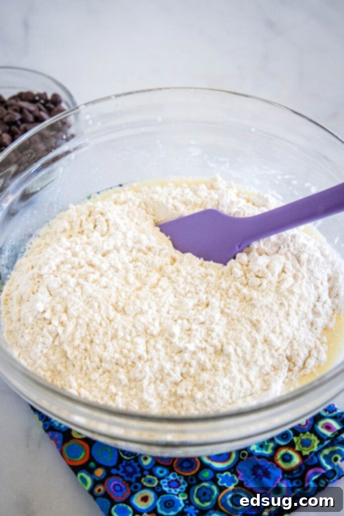 Dry ingredients being added to a bowl of buttermilk muffin batter, ready for gentle folding.