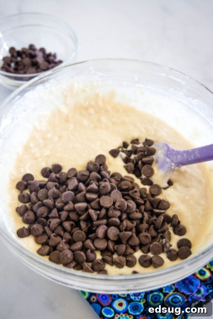 Chocolate chips gently folded into a bowl of buttermilk muffin batter.