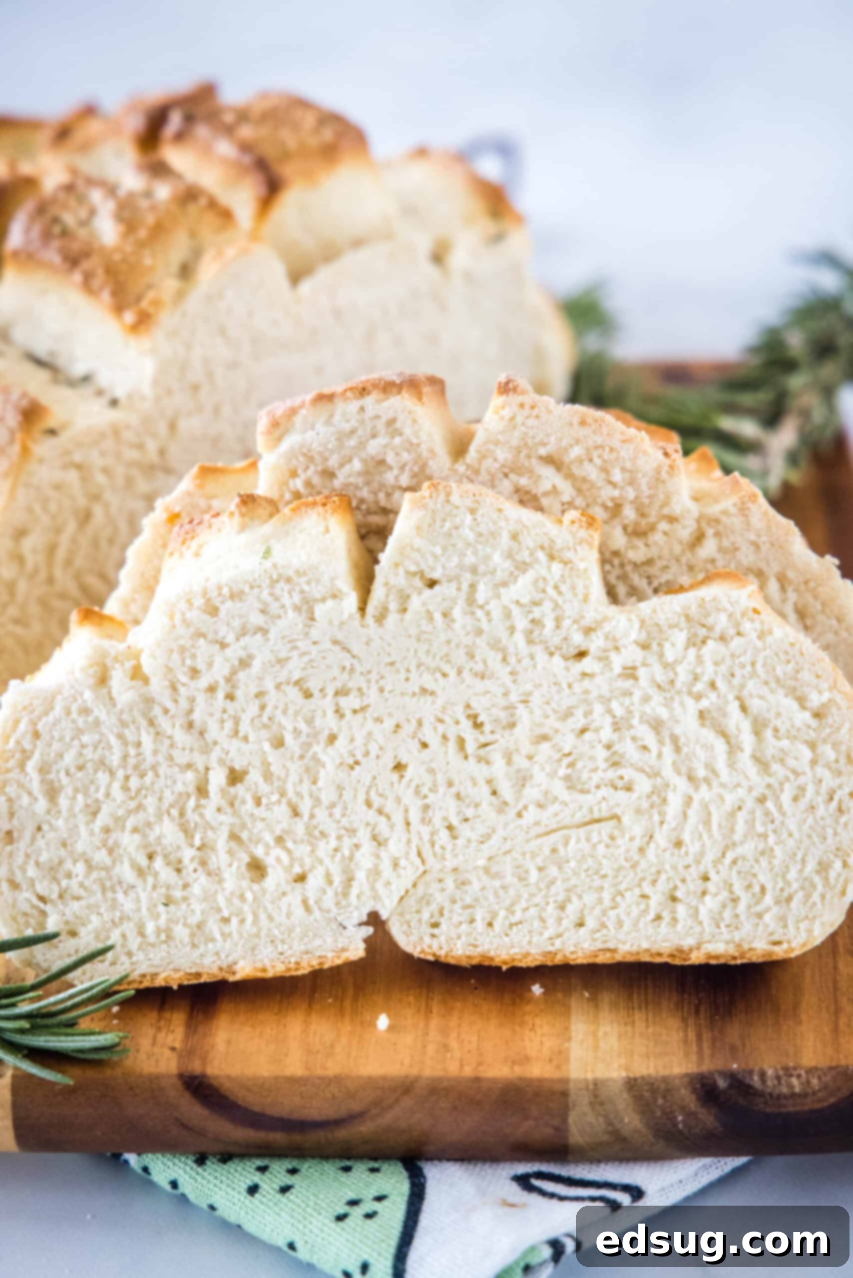 More slices of Amish bread on a wooden cutting board with a full loaf in the background, inviting a delicious meal.