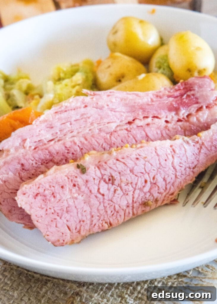Perfect Instant Pot Corned Beef 2 Tender Instant Pot Corned Beef served on a plate with vibrant carrots, fluffy potatoes, and perfectly cooked cabbage