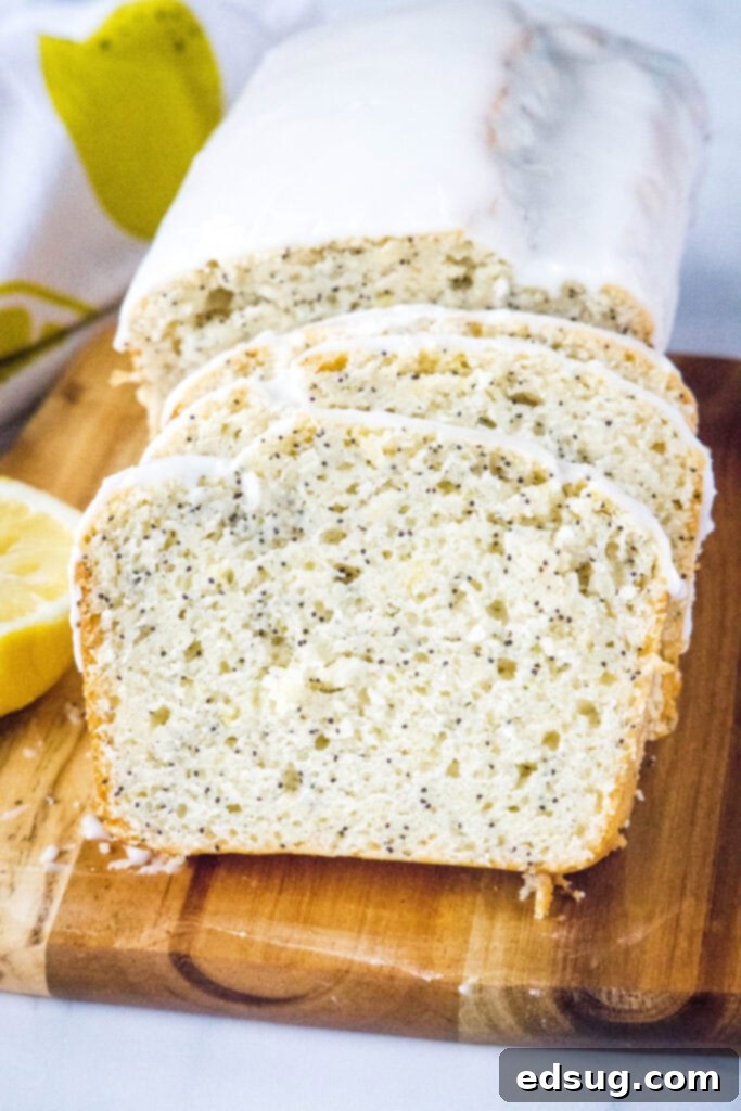 Sliced lemon poppy seed bread on a wooden cutting board, showcasing its moist crumb and poppy seeds.
