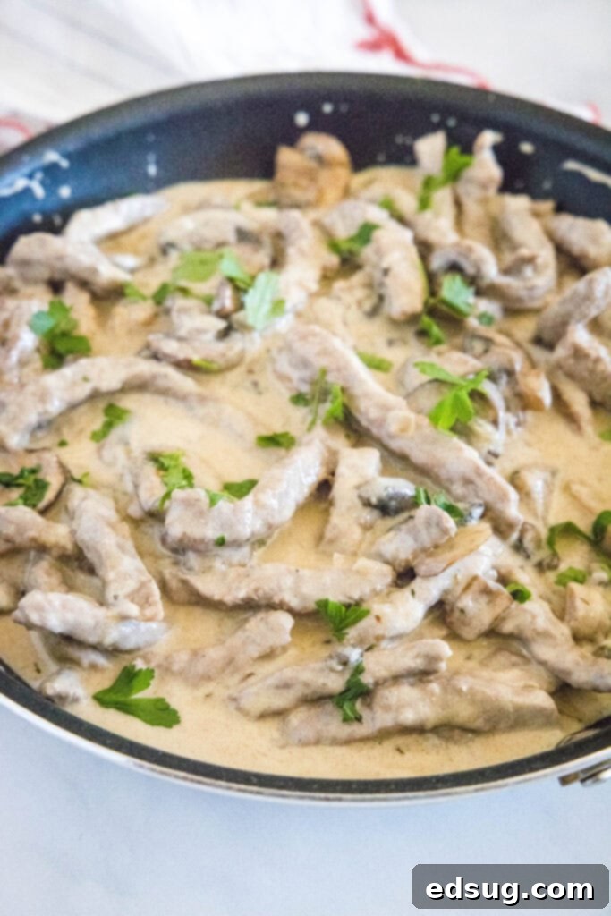 Classic Beef Stroganoff 4 Beef stroganoff simmering in a cast iron skillet with mushrooms and onions