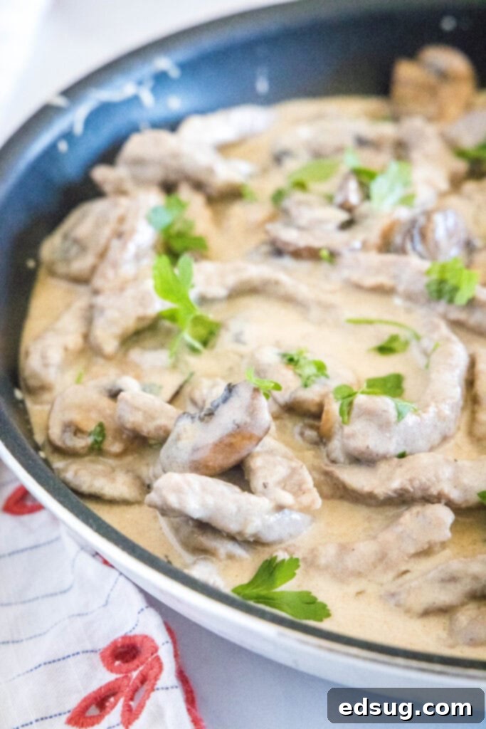 Classic Beef Stroganoff 6 Close-up view of beef stroganoff simmering in a skillet, showing the rich texture of the sauce, beef, and mushrooms.