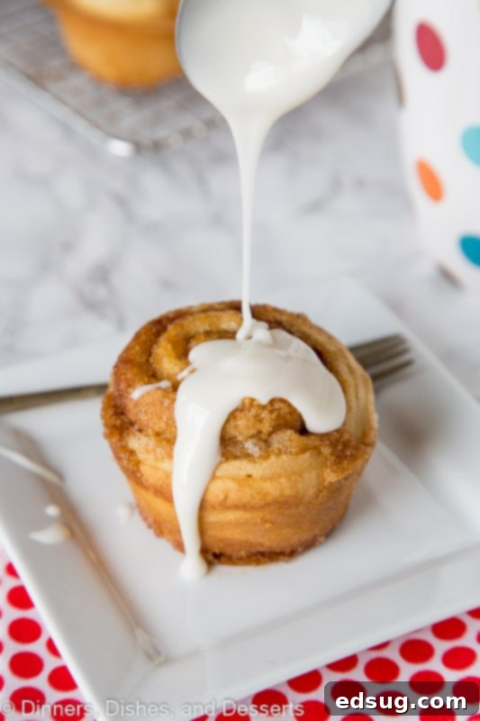 Cinnamon Swirl Muffins 2 cinnamon roll muffin with vanilla glaze being drizzled on top, highlighting the gooey texture