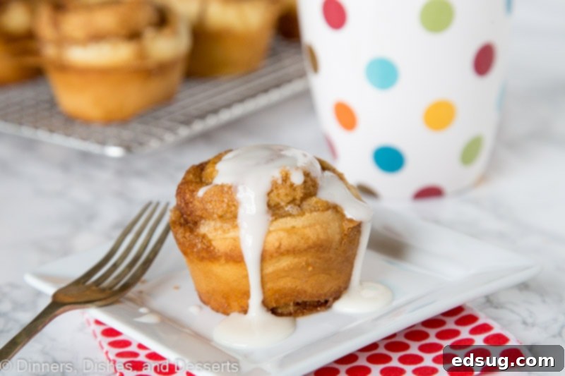 Cinnamon Swirl Muffins 4 Three cinnamon roll muffins on a plate, one being drizzled with vanilla glaze