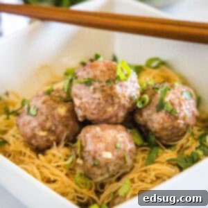 close up asian meatballs over rice noodles in a white bowl