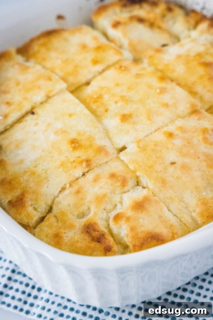 A freshly baked batch of golden-brown butter swim biscuits, still in their 8-inch baking pan, showing off their crispy edges and soft tops, ready to be served warm.