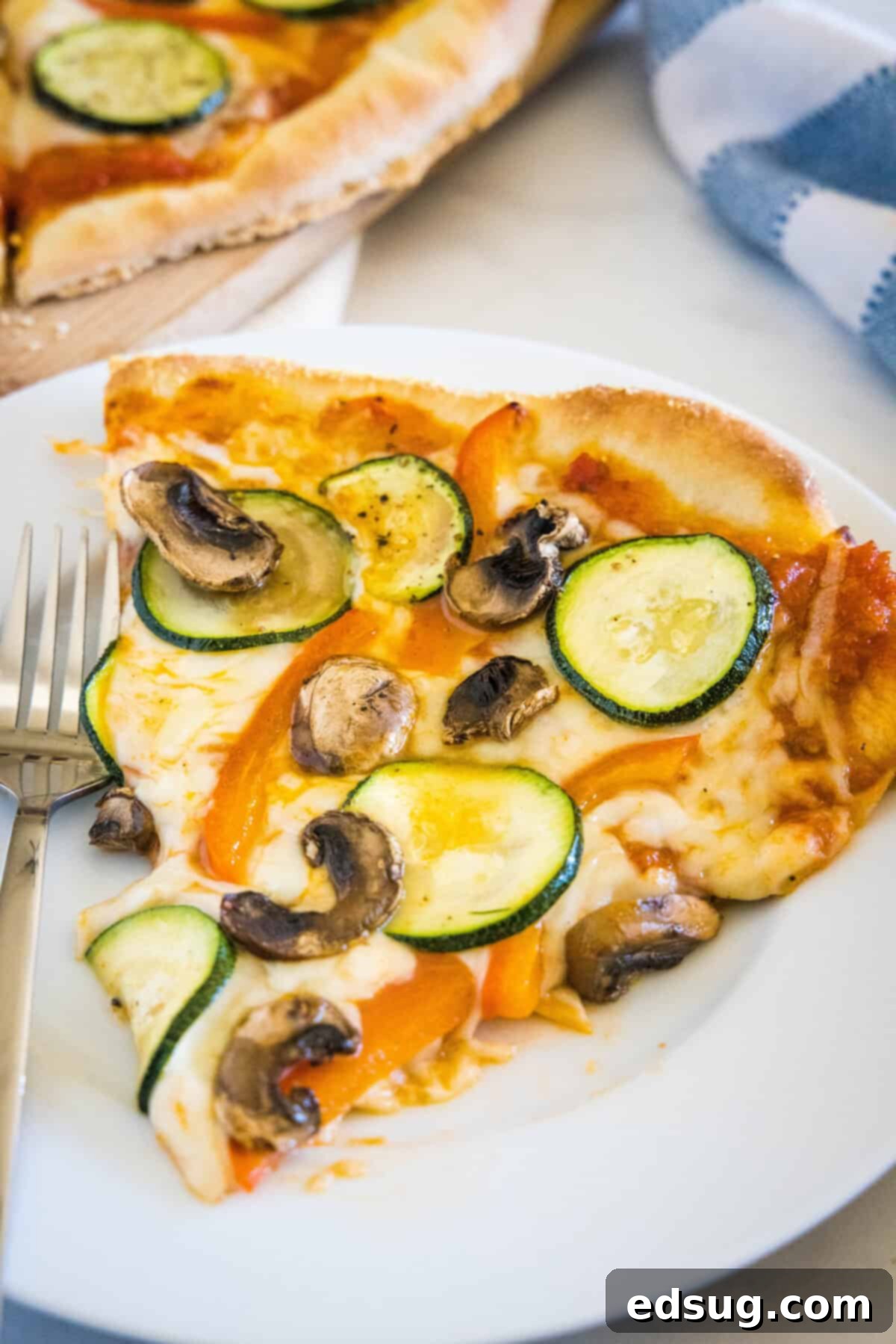 Gourmet Roasted Vegetable Pizza 3 A single slice of roasted vegetable pizza on a white plate, showing the melted cheese and colorful veggies.