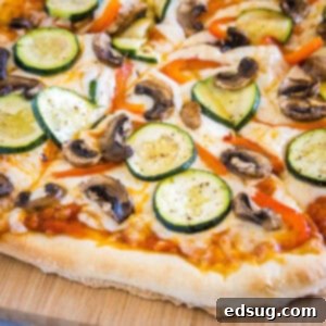 Gourmet Roasted Vegetable Pizza 5 Close-up of a perfectly baked, sliced roasted vegetable pizza on a wooden cutting board, ready to be served.