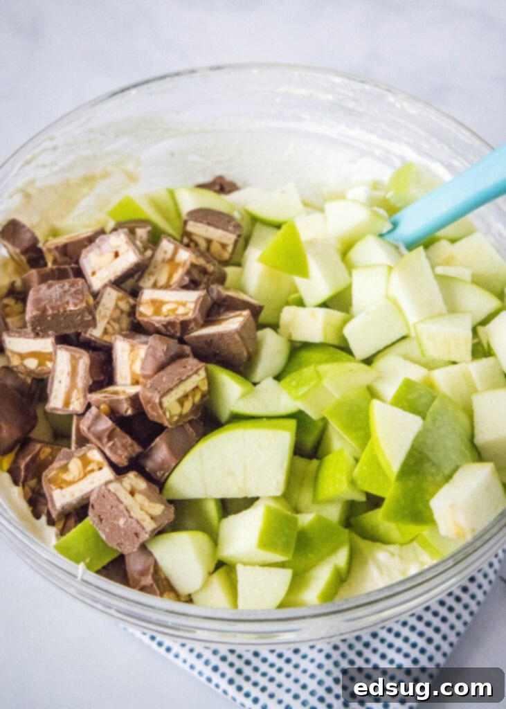 apples and snickers added to a mixing bowl