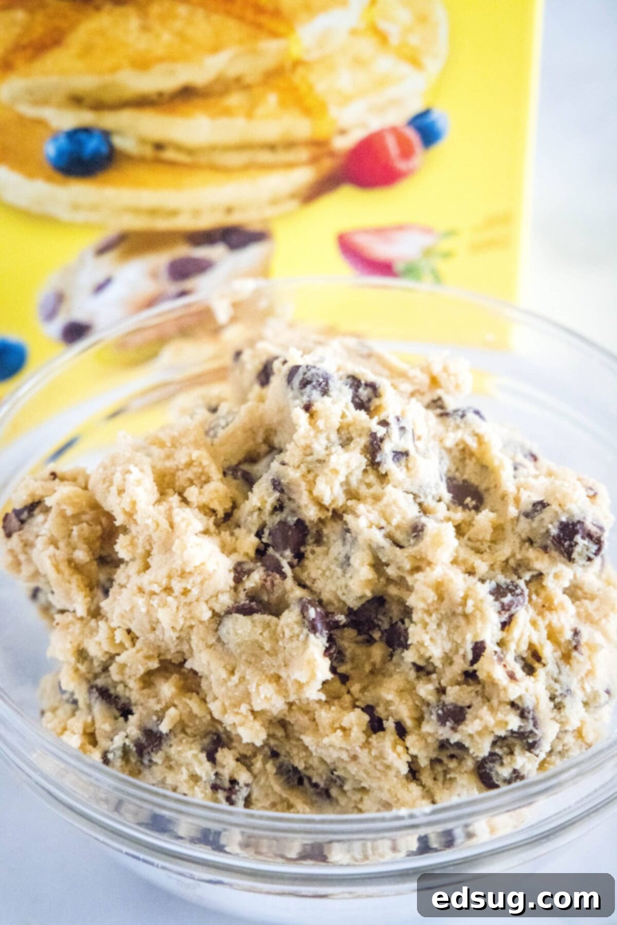 A mixing bowl full of chocolate chip cookie dough in front of a box of Bisquick
