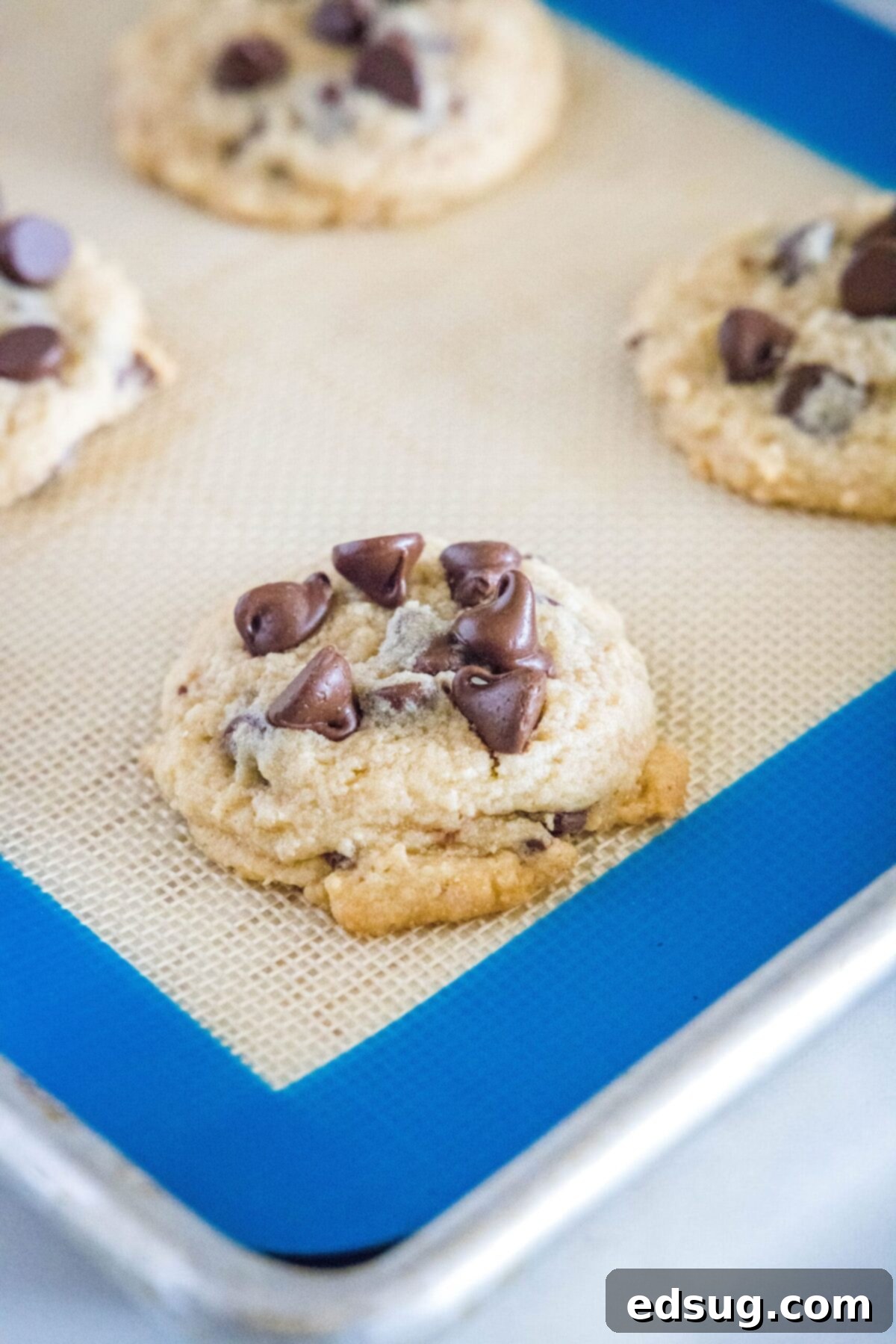 Close up of baked chocolate chip cookies on a silicone mat on a baking sheet