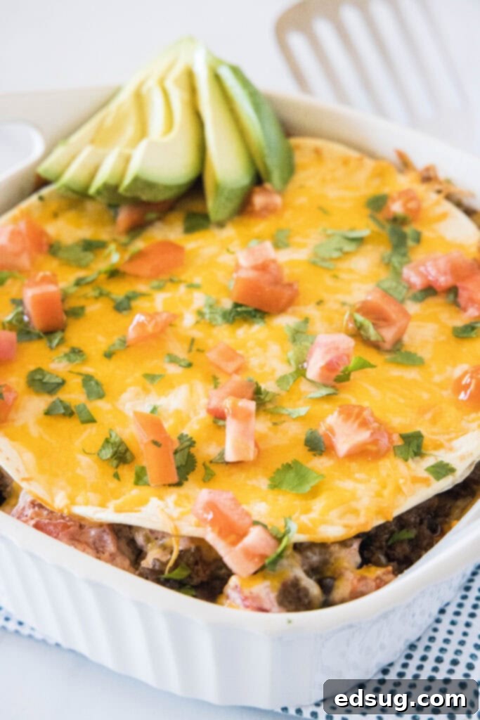 Burrito Bake 5 A slice of Burrito Casserole topped with fresh tomatoes, cilantro, and avocado, ready to eat.