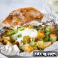 Foil Packet Grilled Potatoes 6 grilled potato pack on a plate with a pork chop