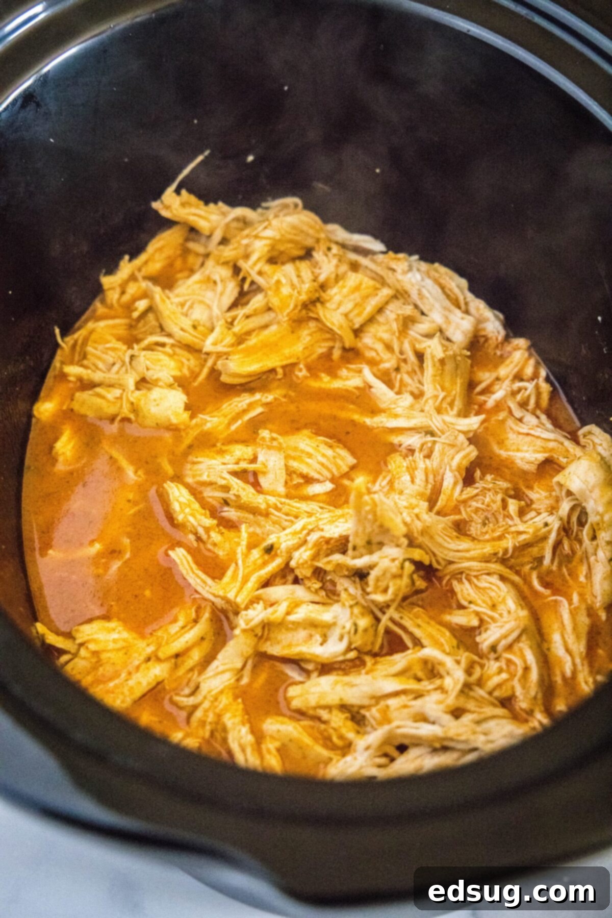 Shredded chicken in a slow cooker with a buffalo sauce