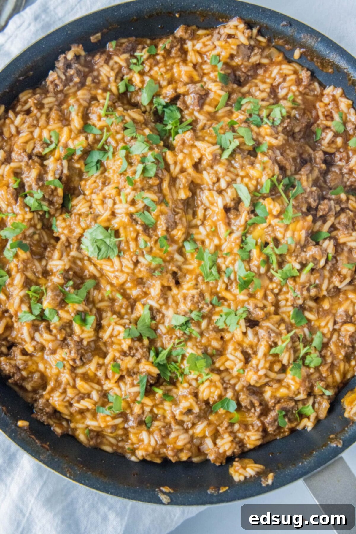 Overhead view of a skillet filled with beefy taco rice, topped with cilantro