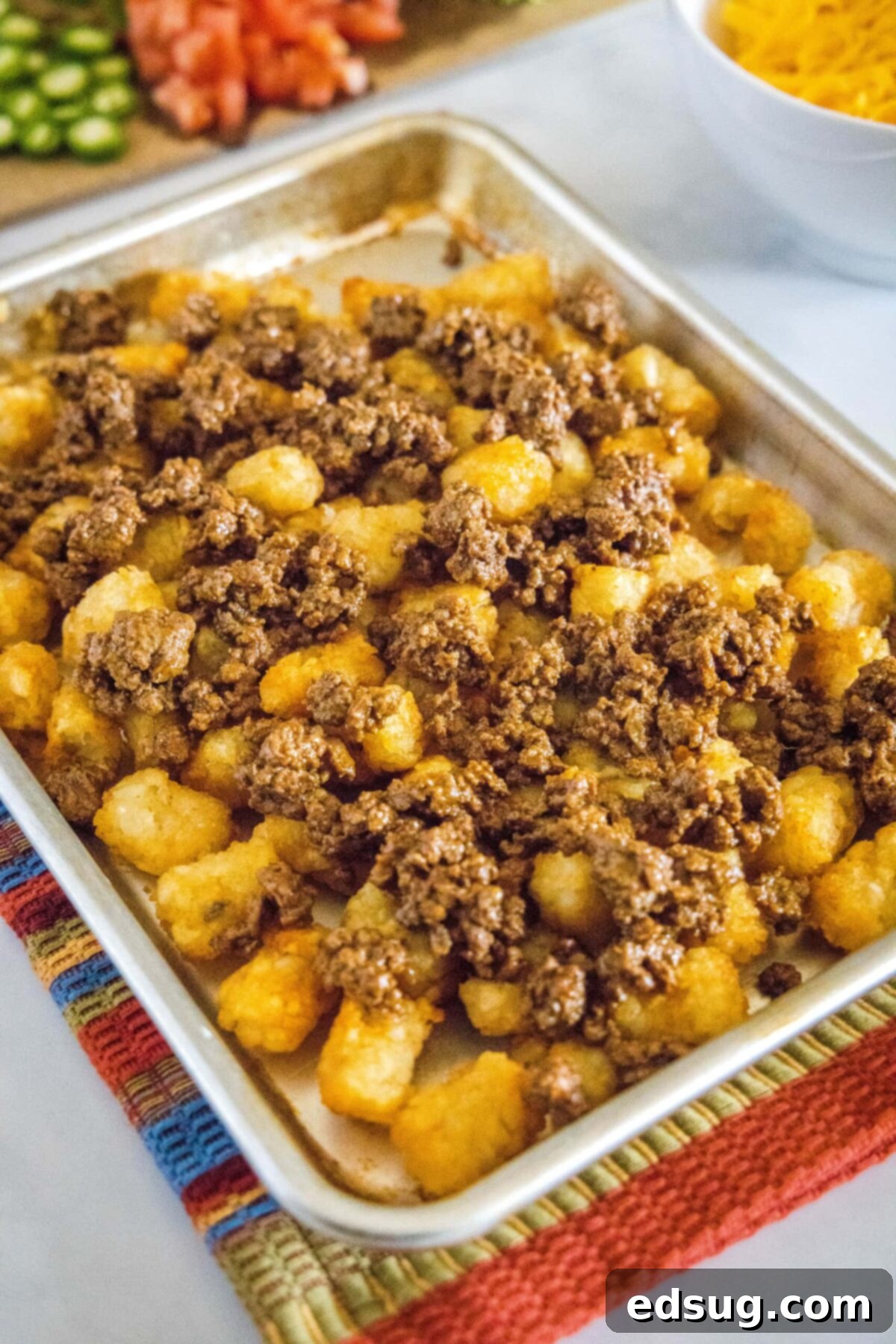 A baking sheet filled with tater tots covered in ground beef