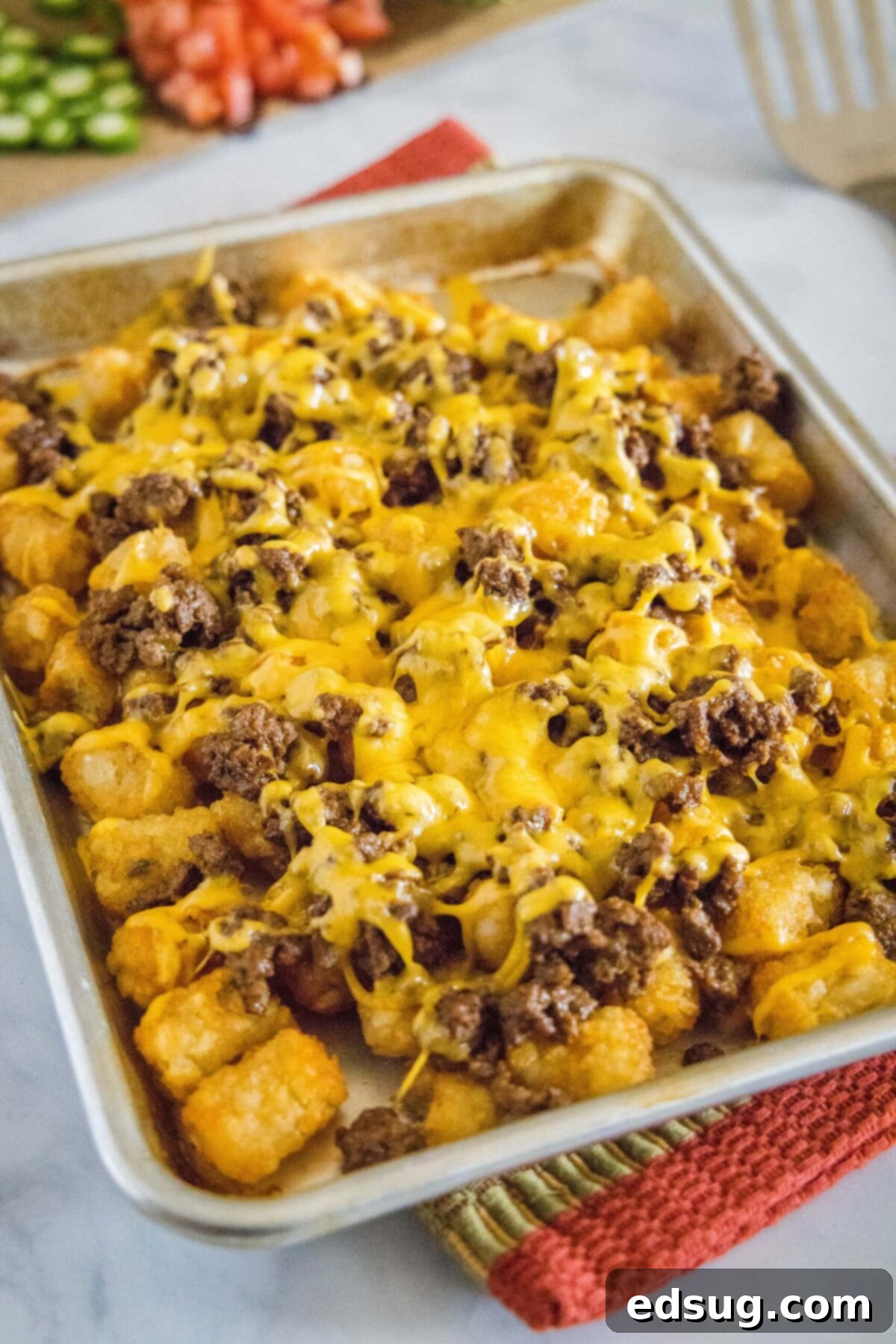 A baking sheet filled with tater tots, ground beef, and melty cheese