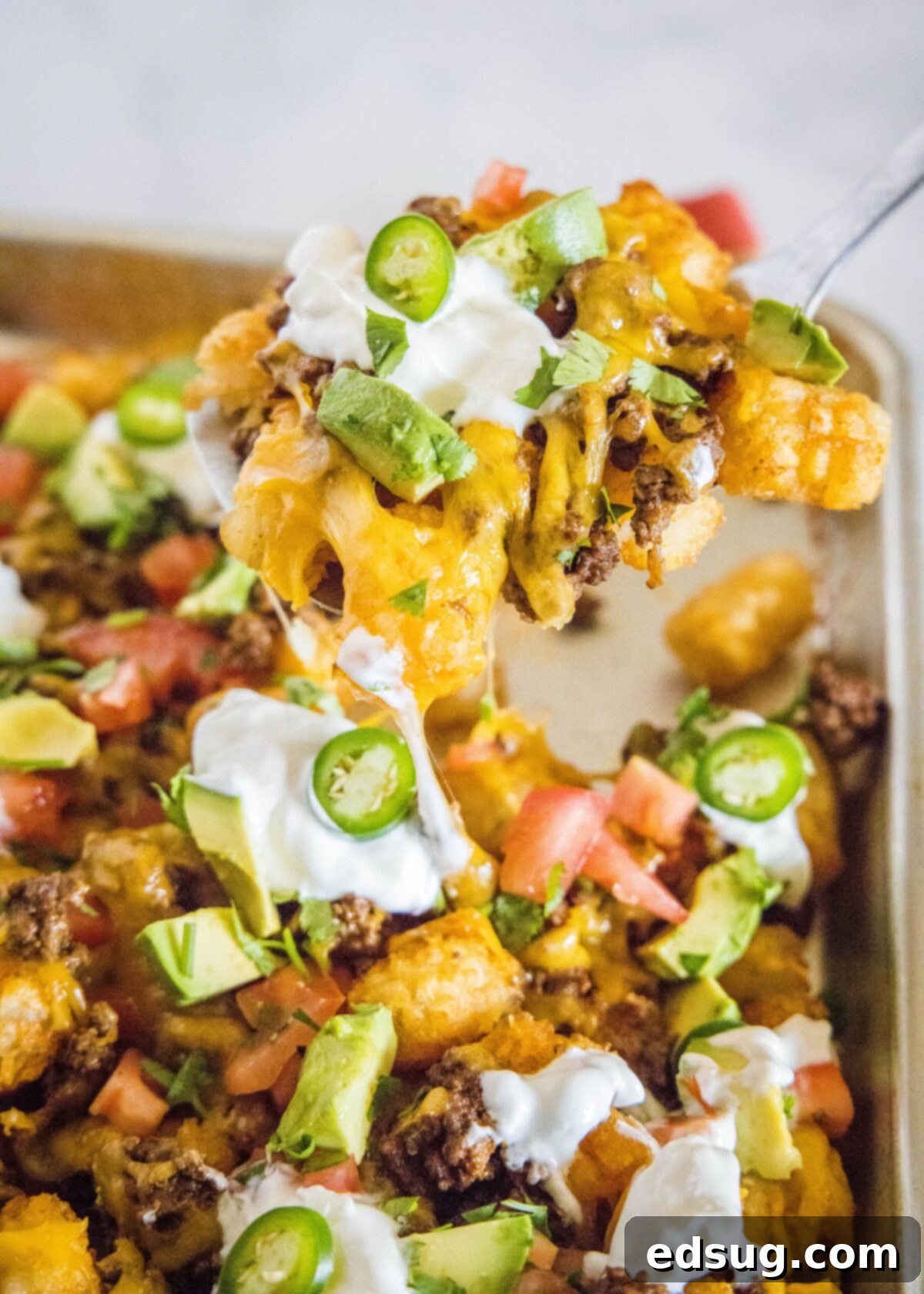 Close-up of a perfectly loaded totchos platter, ready to be served, with vibrant toppings