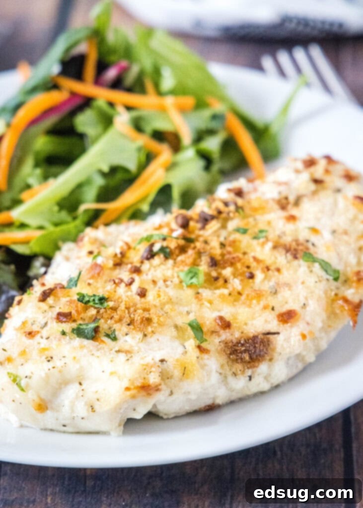 Golden Baked Caesar Chicken 6 caesar chicken on a white plate with salad in the background