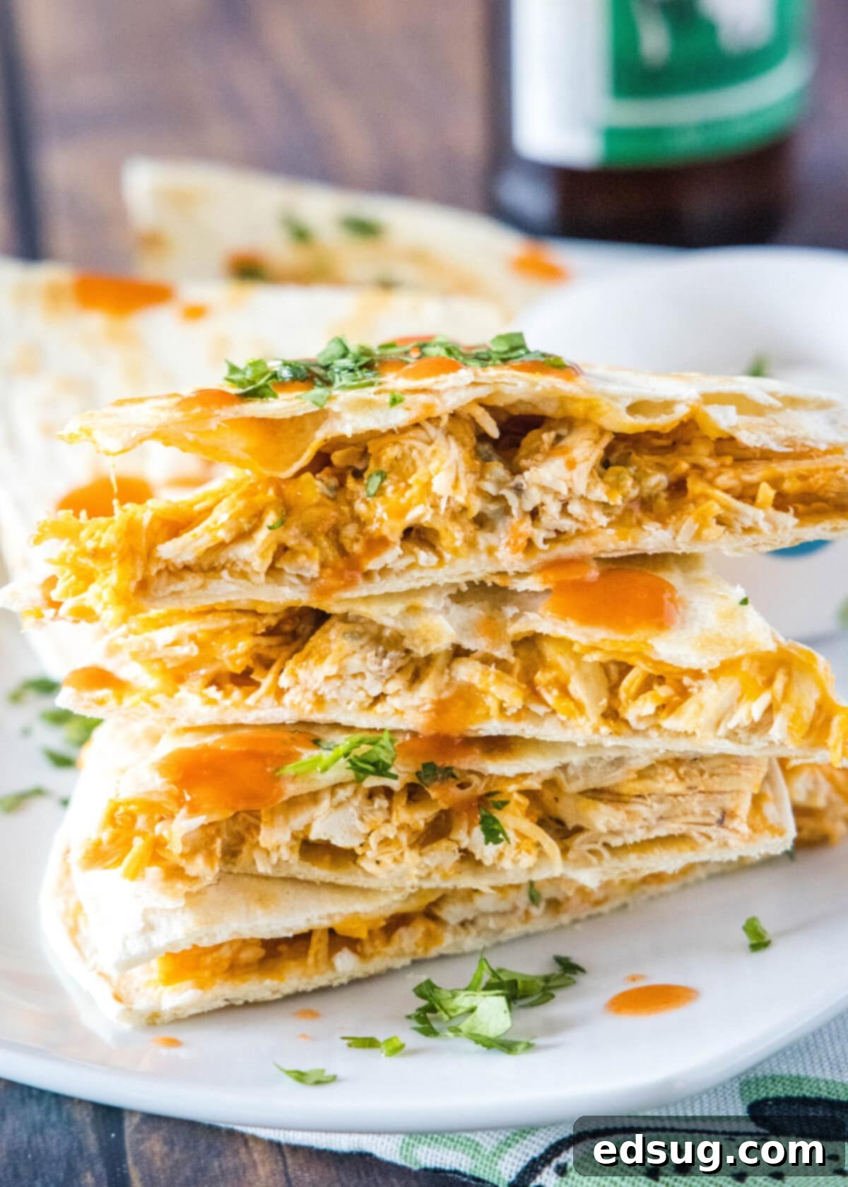 This easy homemade buffalo chicken quesadilla recipe is loaded with juicy chicken, melty cheese, and spicy wing sauce. Close up of a stack of buffalo chicken quesadilla triangles, topped with cilantro