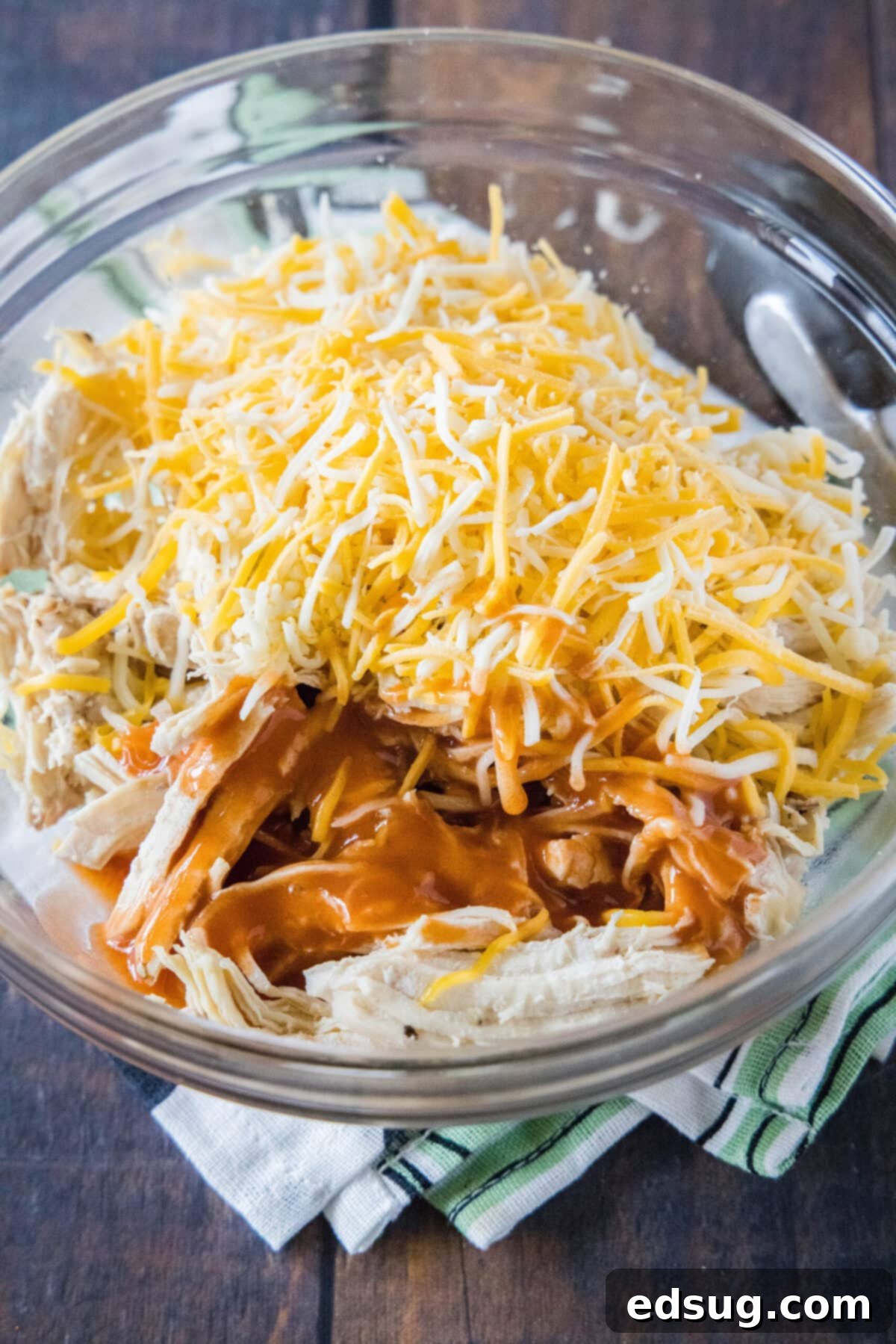 This easy homemade buffalo chicken quesadilla recipe is loaded with juicy chicken, melty cheese, and spicy wing sauce. A mixing bowl filled with shredded chicken, wing sauce, and shredded cheese