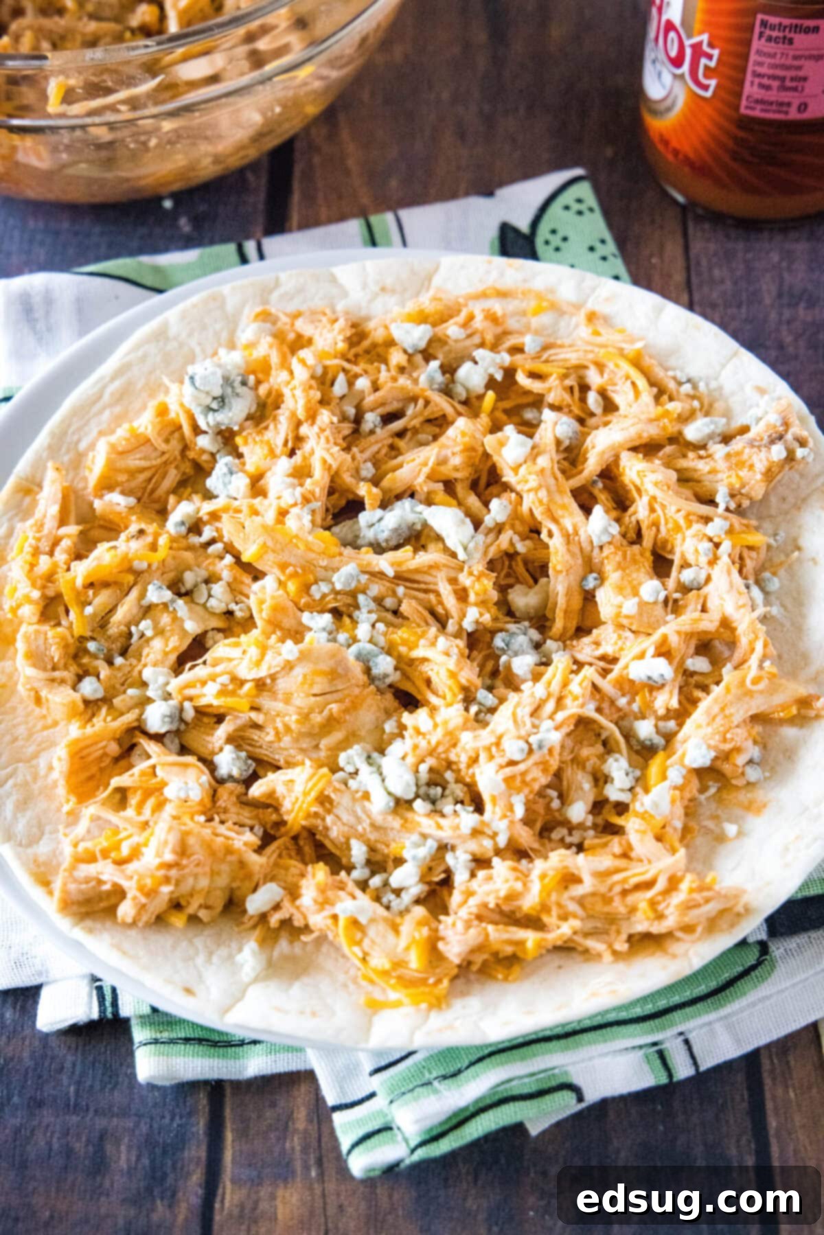 This easy homemade buffalo chicken quesadilla recipe is loaded with juicy chicken, melty cheese, and spicy wing sauce. A plate with a tortilla topped with buffalo chicken and cheese mixture, topped with blue cheese crumbles