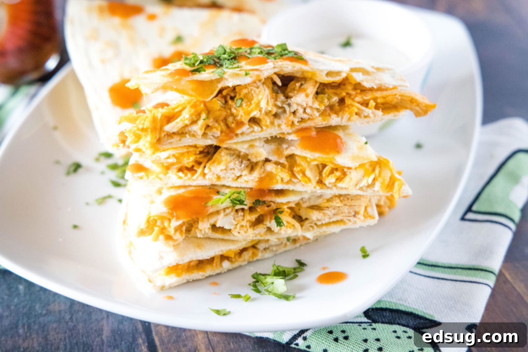 This easy homemade buffalo chicken quesadilla recipe is loaded with juicy chicken, melty cheese, and spicy wing sauce. Close up of a plate with a stack of buffalo chicken quesadilla triangles