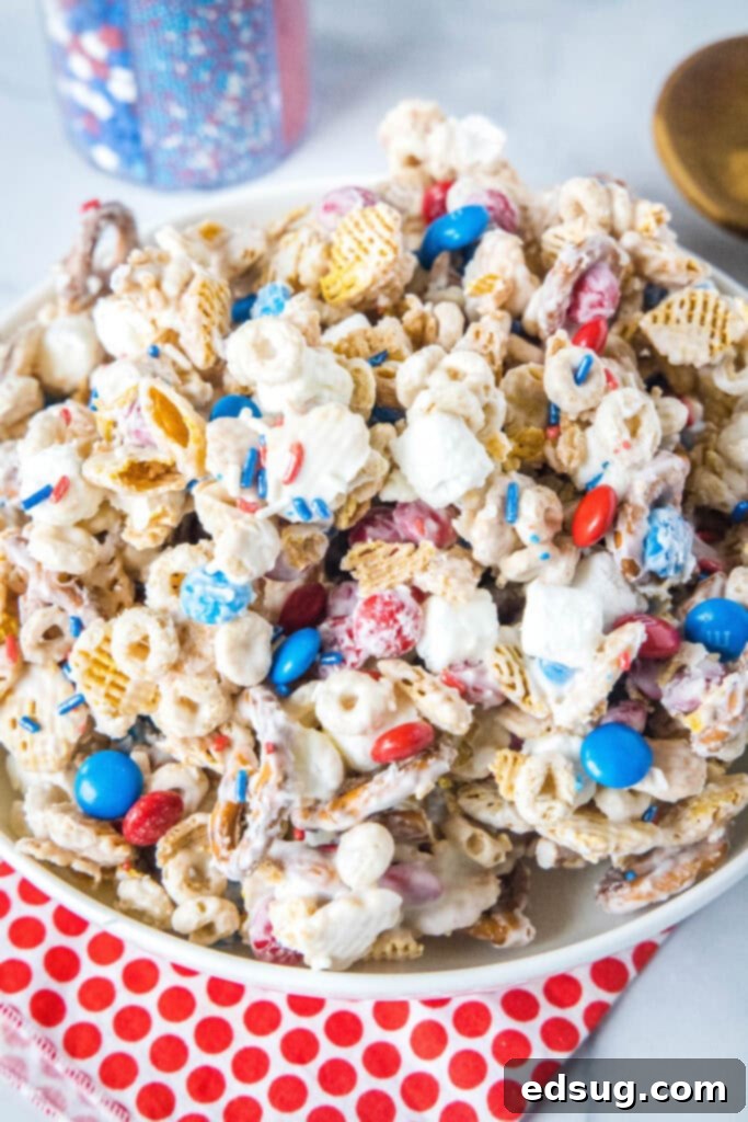 Stars & Stripes Party Blend 2 a white serving bowl of 4th of july snack mix, featuring red, white, and blue candies, pretzels, and cereals