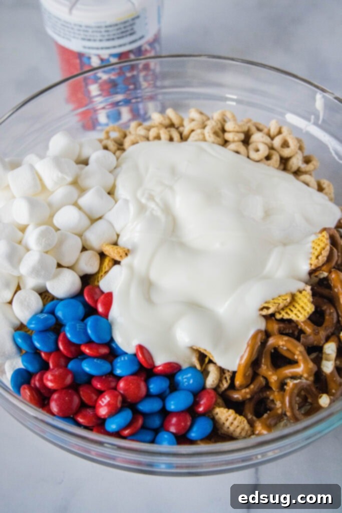 Stars & Stripes Party Blend 4 pouring white chocolate over snack mix ingredients in a large bowl