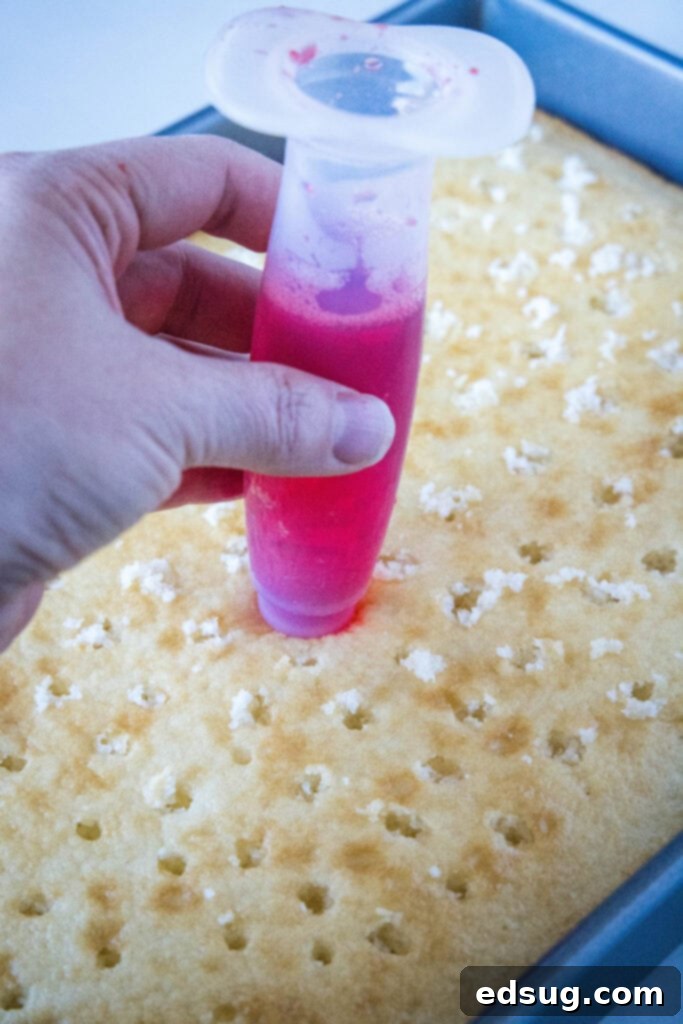 Adding red Jell-O into poke holes on a white cake using a straw