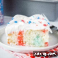 A beautiful slice of 4th of July Poke Cake on a white plate, showcasing the red and blue Jell-O streaks within the white cake and fluffy whipped cream topping.