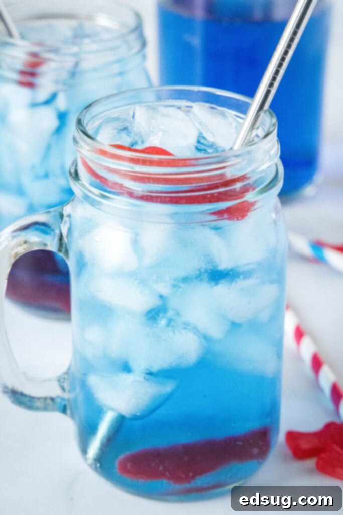 AquaPulse Dynamics 2 Glass of vibrant blue Sonic Ocean Water with a straw and Swedish fish garnish, perfect for summer.