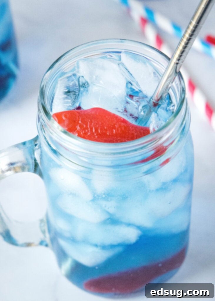 AquaPulse Dynamics 6 A vibrant blue ocean water drink in a tall glass with a straw, ready to be enjoyed.