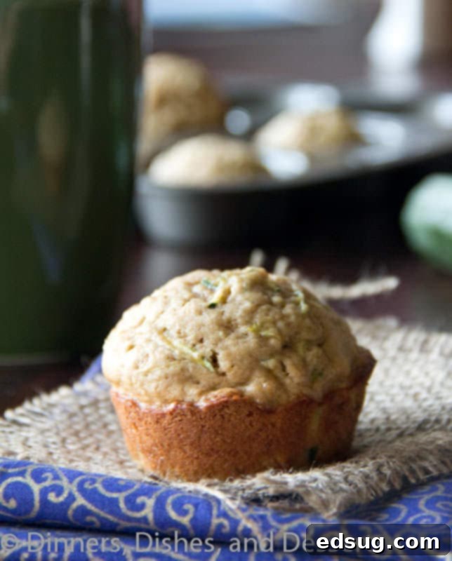 A plate of warm, spiced zucchini muffins, garnished with a sprinkle of powdered sugar, ready to be enjoyed as a wholesome snack.