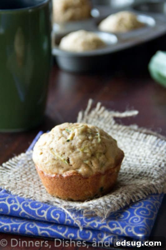 A stack of golden zucchini muffins on a clean white napkin, showcasing their fluffy texture and delicious appearance.