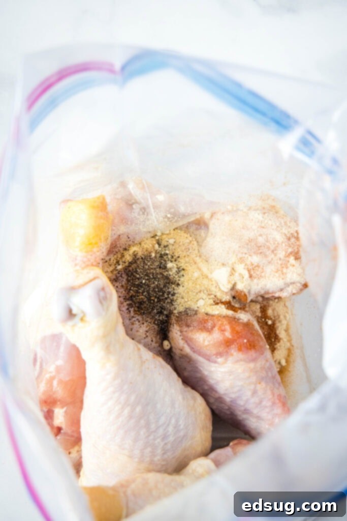 Fall-Off-The-Bone Slow Cooker Drumsticks 3 Someone coating chicken legs in a flavorful seasoning mix in a large bowl.