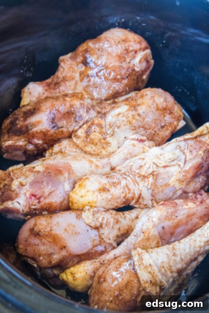 Fall-Off-The-Bone Slow Cooker Drumsticks 4 Seasoned chicken drumsticks arranged neatly in the base of a crockpot, ready for slow cooking.