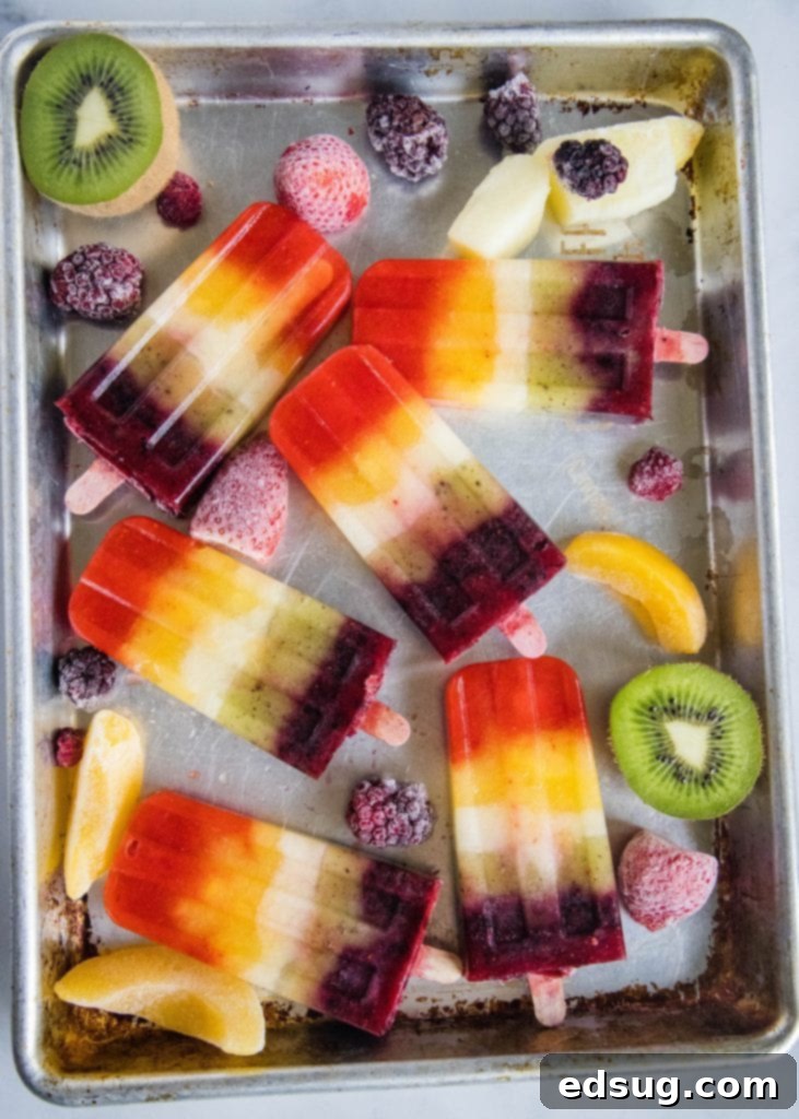 rainbow popsicles on a baking tray with frozen fruit