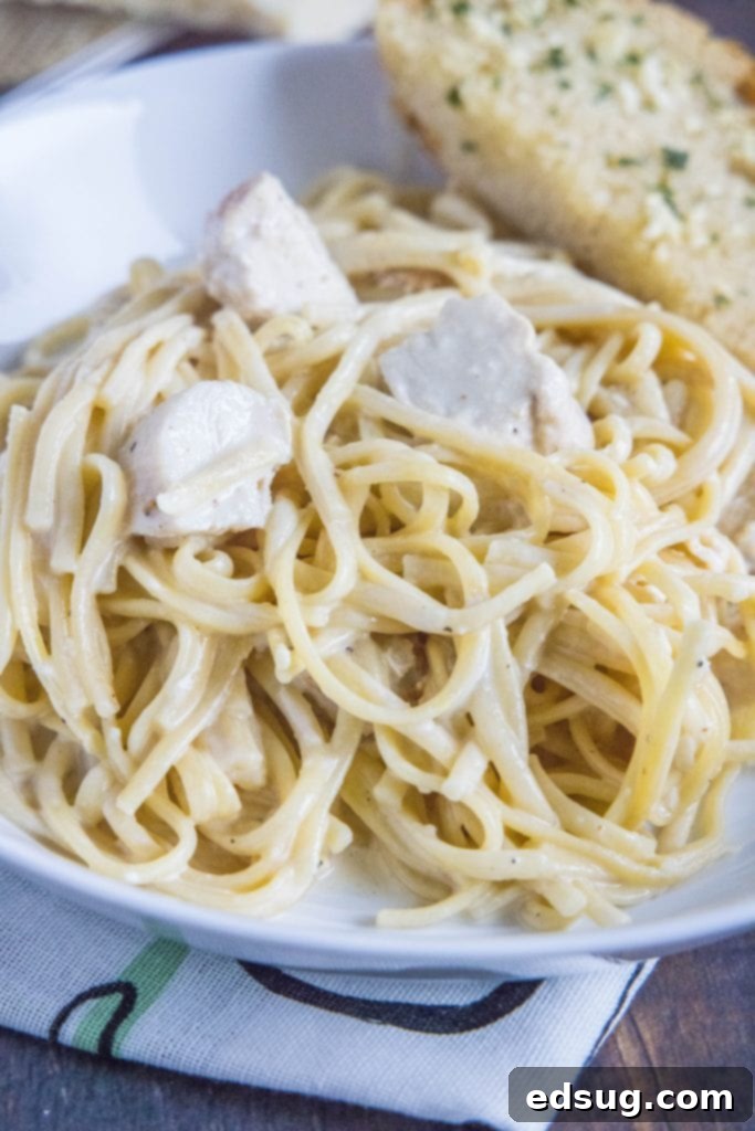 One Pot Wonder Chicken Alfredo 6 a white bowl filled with Instant Pot chicken alfredo and a side of garlic bread