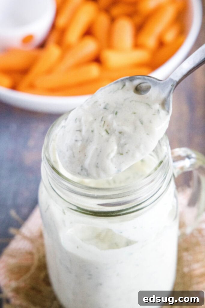 A spoonful of rich, creamy homemade ranch dressing being lifted from a bowl.