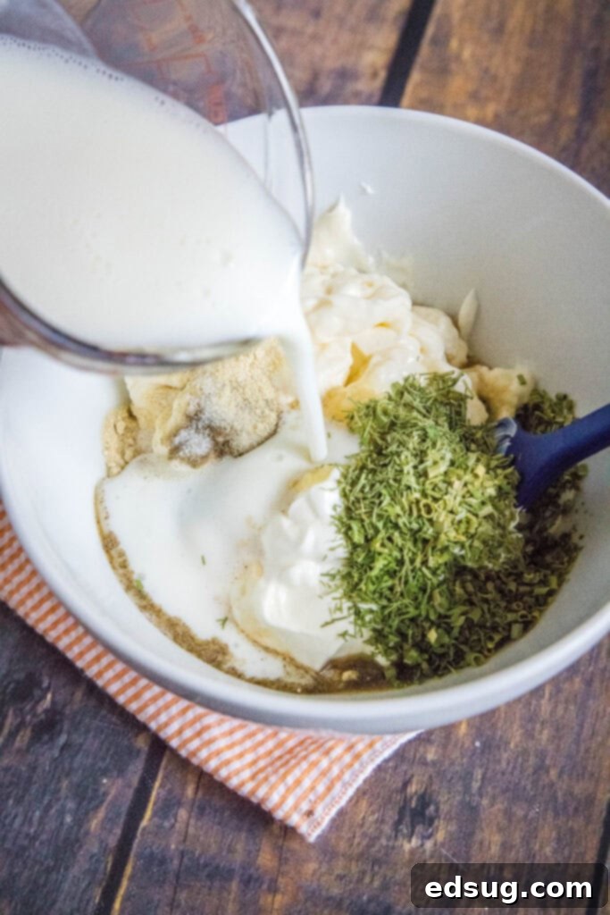 Pouring fresh buttermilk into a bowl of other ranch dressing ingredients.