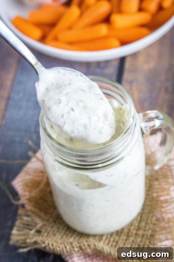 A spoon lifting a generous portion of thick, creamy ranch dressing.